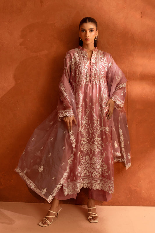 Woman wearing a pink embroidered dress against an orange wall