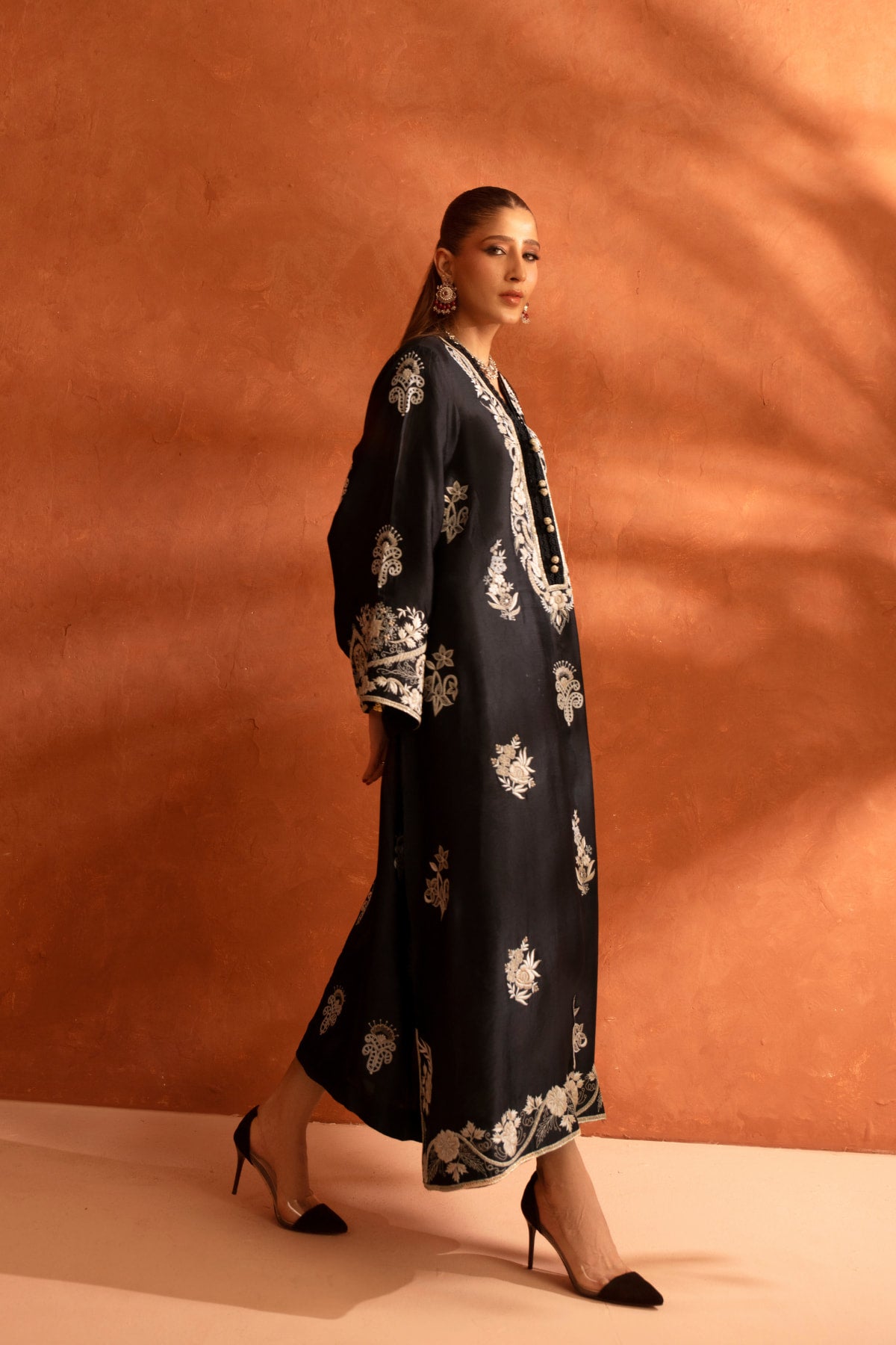 Woman wearing a dark floral kaftan against an orange background