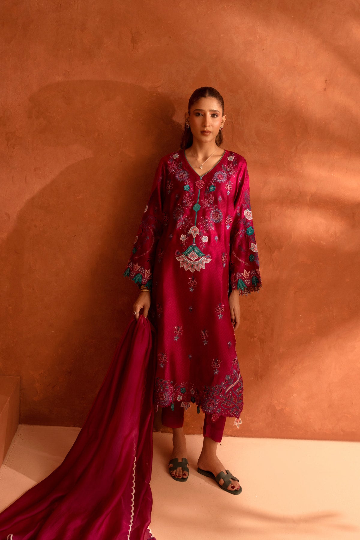 Woman wearing a red embroidered outfit against a brown background
