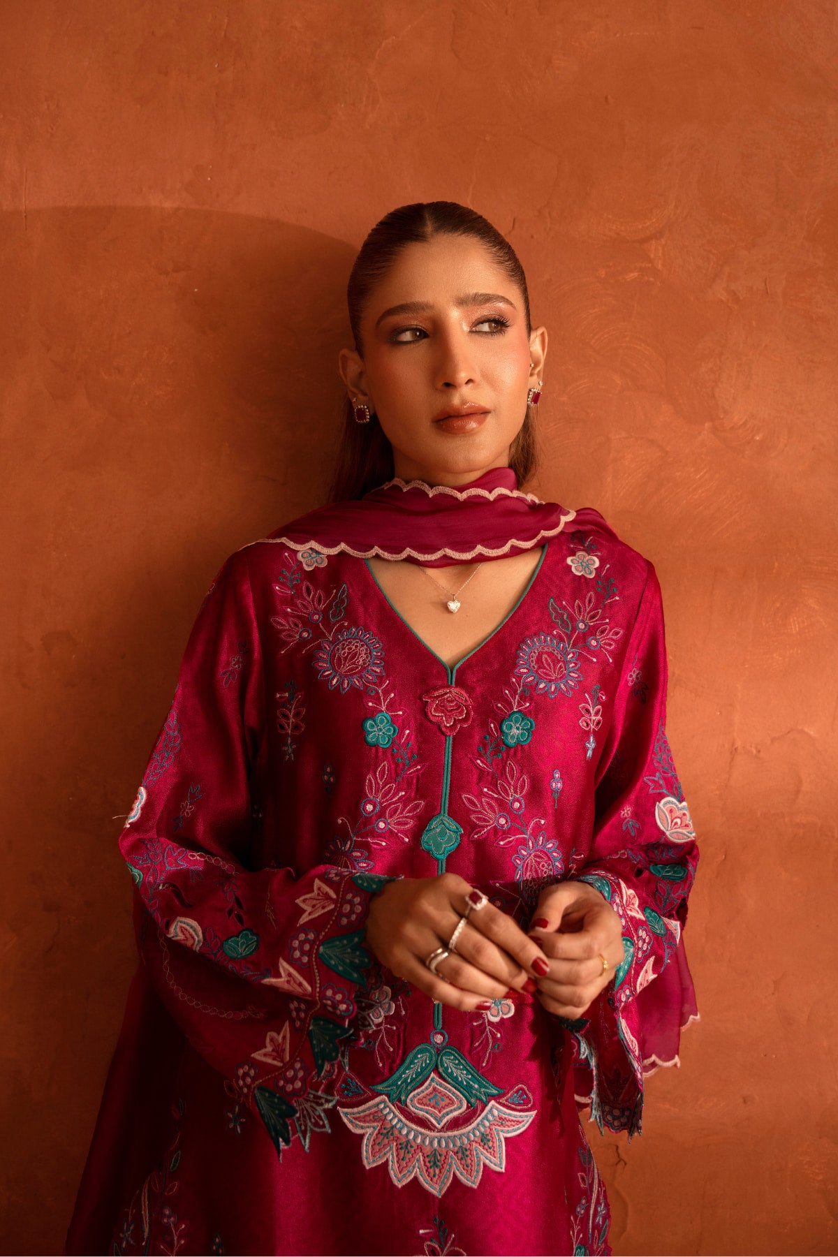 Woman wearing a red embroidered traditional outfit against an orange background
